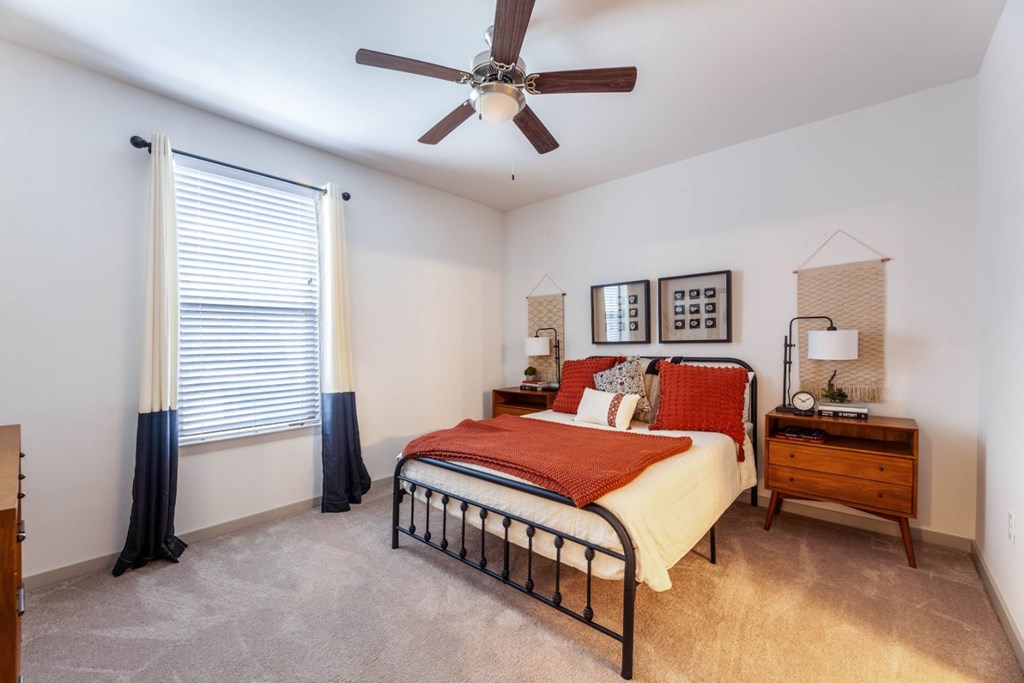 A bedroom with a bed, dresser, and window with curtains.