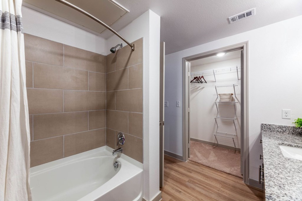 A bathroom with a white tub and a white chair in the closet.