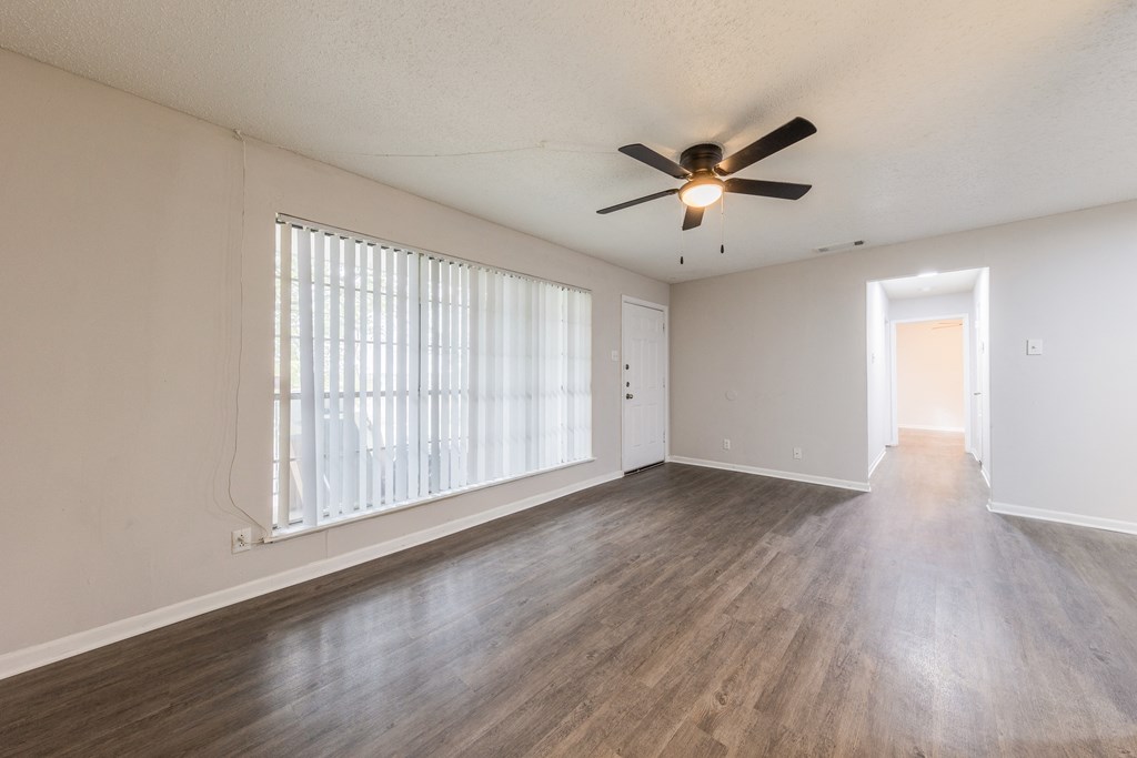an empty living room with a ceiling fan