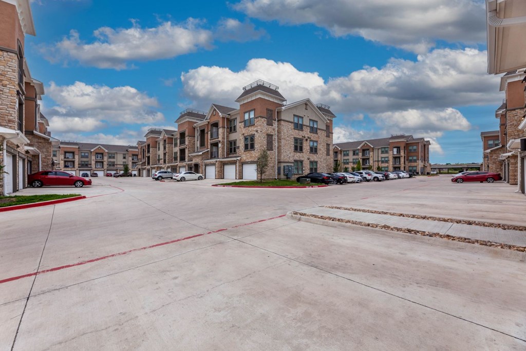 A parking lot in front of a large apartment complex.