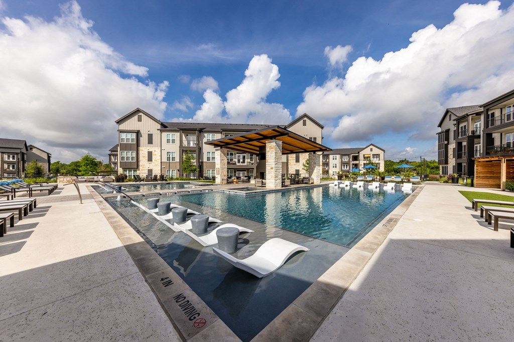A large pool with a slide and sun loungers in front of apartment buildings.