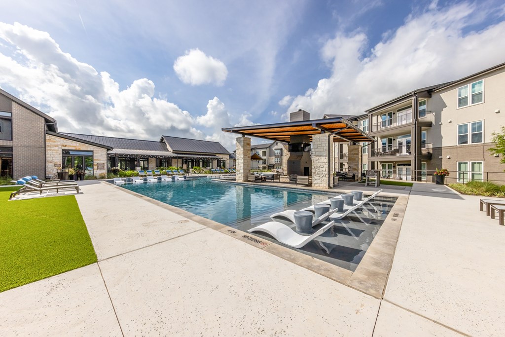 A large outdoor swimming pool with loungers and a building in the background.