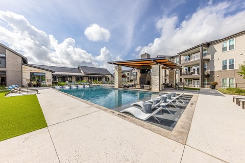 A large outdoor swimming pool with loungers and a building in the background.