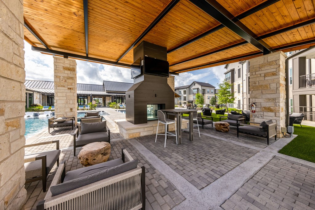 A patio with a table and chairs and a pool in the background.