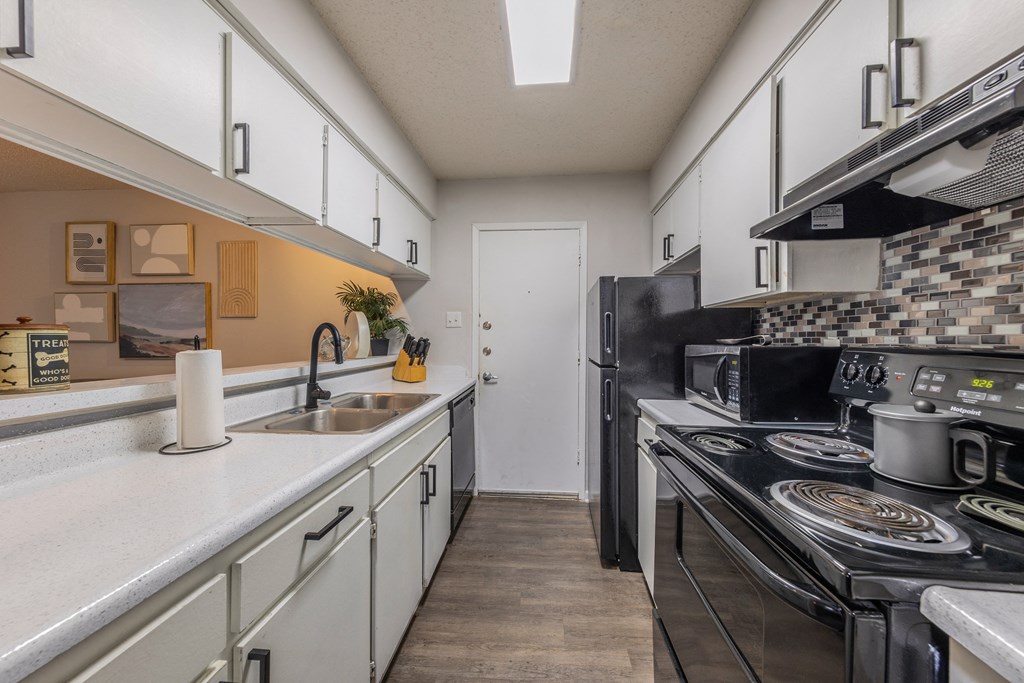 a kitchen with white cabinets and black appliances