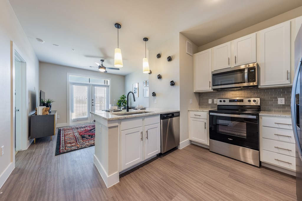 A kitchen with white cabinets and a wooden floor.