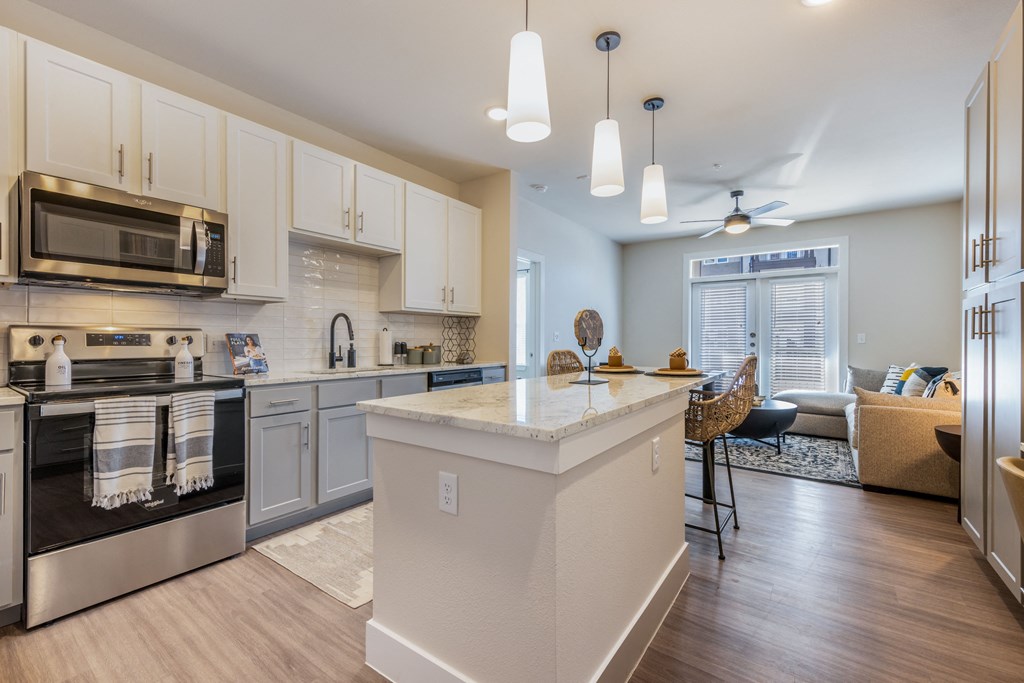 A kitchen with a white island and stainless steel appliances.