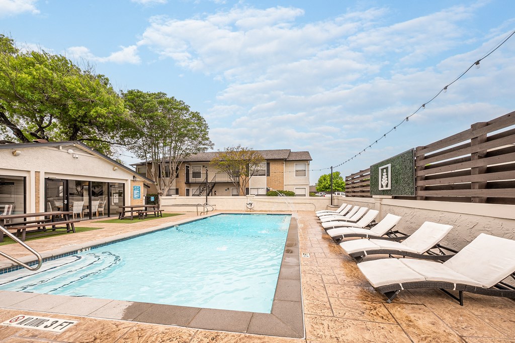 a pool with lounge chairs and a building in the background