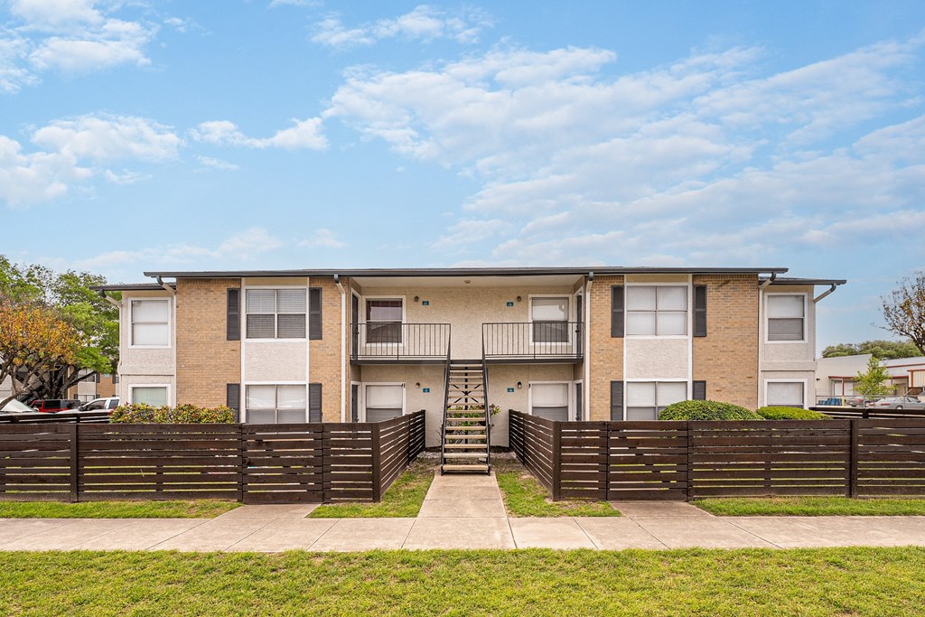 a brick apartment building with a wooden fence in front of it