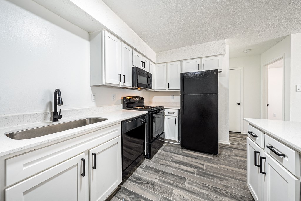 a kitchen with white cabinets and a black refrigerator