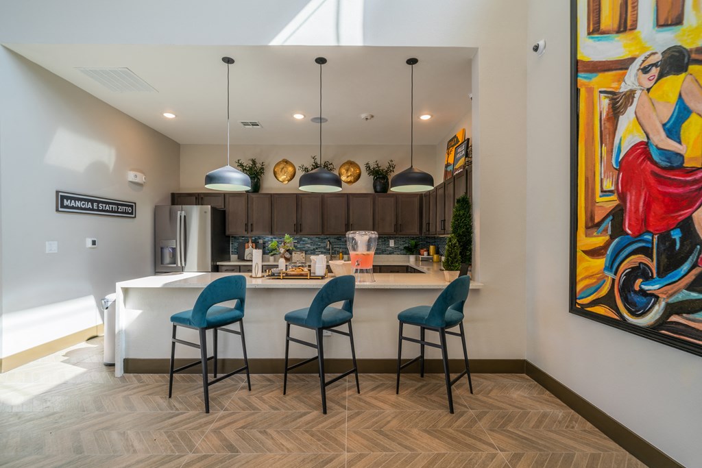 a kitchen and dining area with blue chairs and a colorful painting on the wall