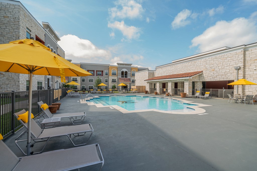 a pool with lounge chairs and umbrellas at the enclave at woodbridge apartments in sugar