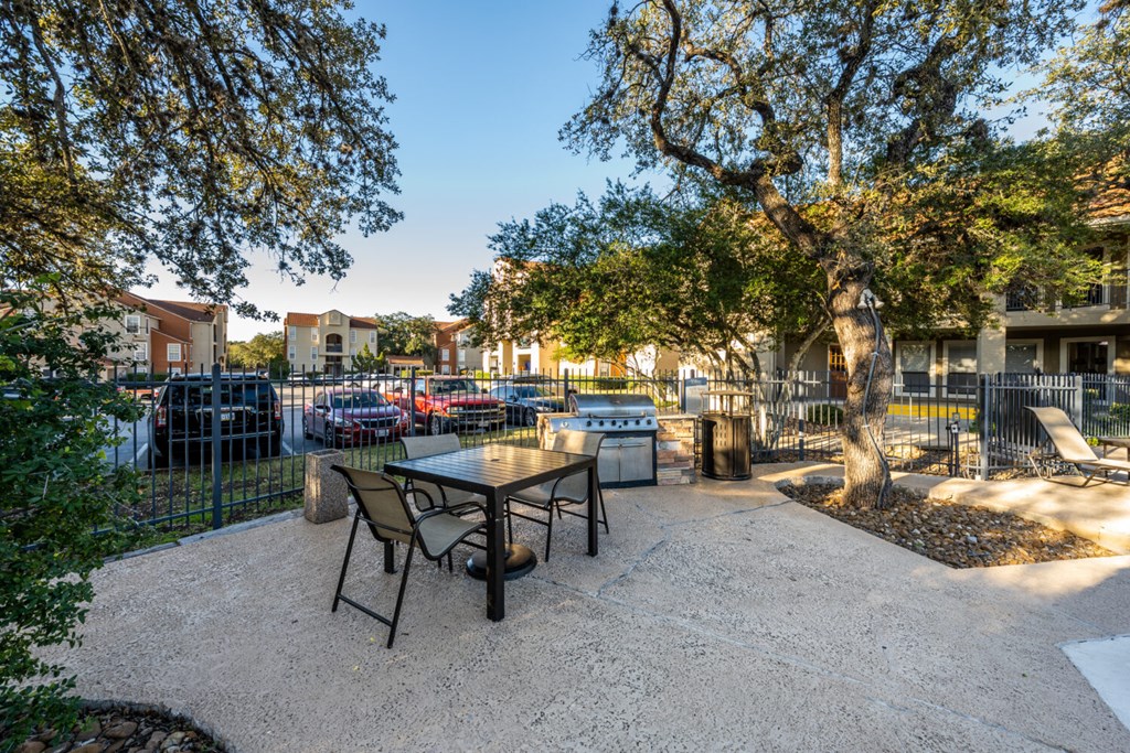 A patio with a table and chairs surrounded by trees.