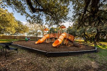 A playground with a slide and a green lawn.