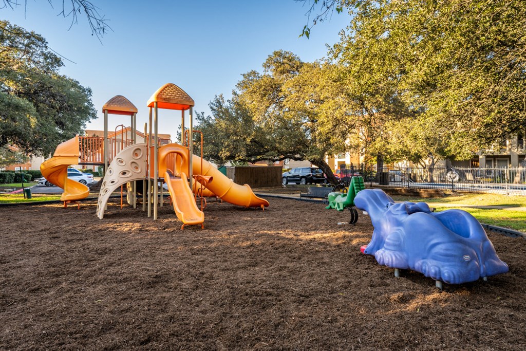 A playground with a yellow and orange slide and a blue slide.