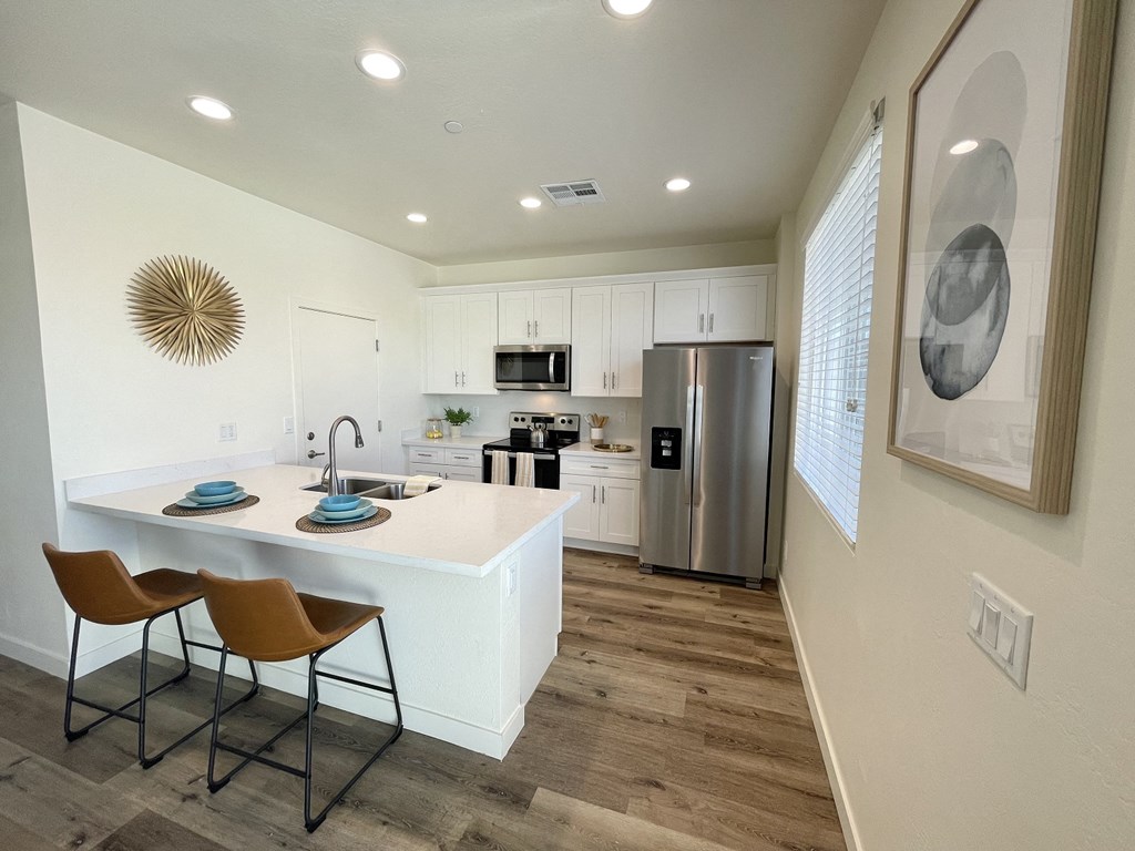 an open kitchen and dining area with a stainless steel refrigerator