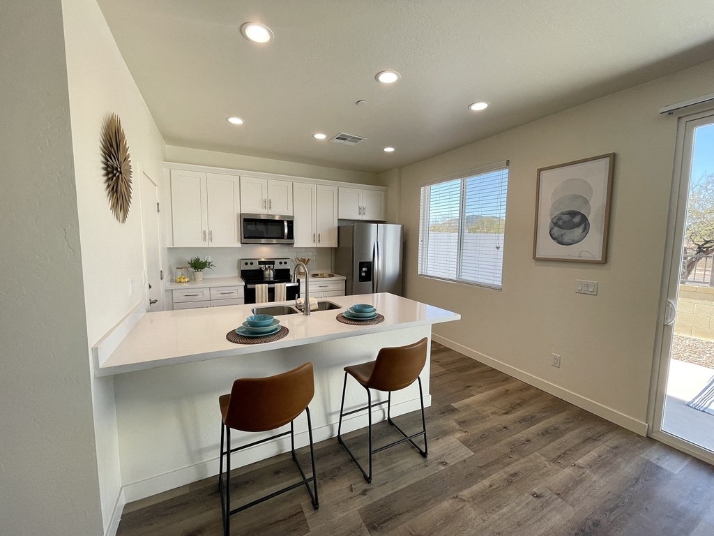 a kitchen with a white counter top and a island with two chairs