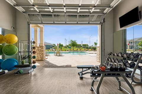 A gym with a view of a pool and a playground.
