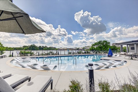 A large outdoor swimming pool surrounded by lounge chairs and umbrellas.