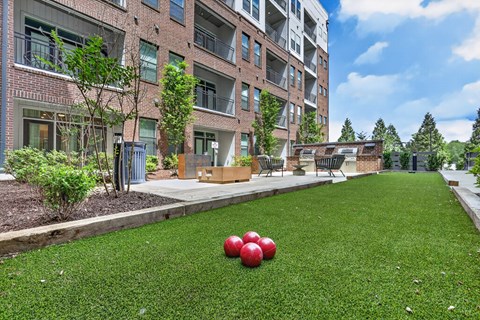 Two red apples are on the grass in front of a building.