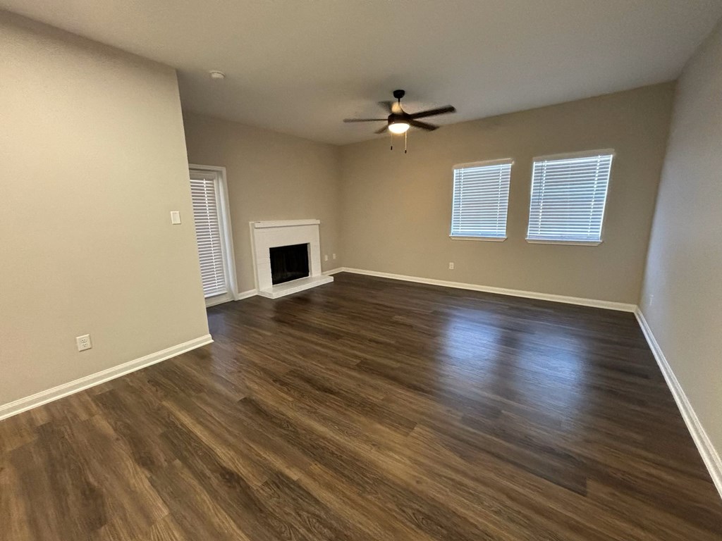 an empty living room with a ceiling fan and a fireplace