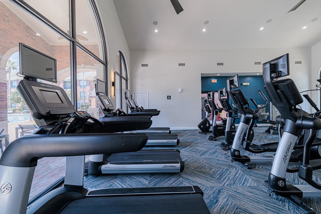 a room filled with cardio equipment and a large window
