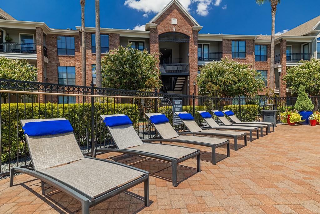 a row of chaise lounges on a brick patio in front of a brick building