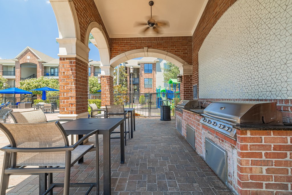 a covered patio with a grill and tables and chairs