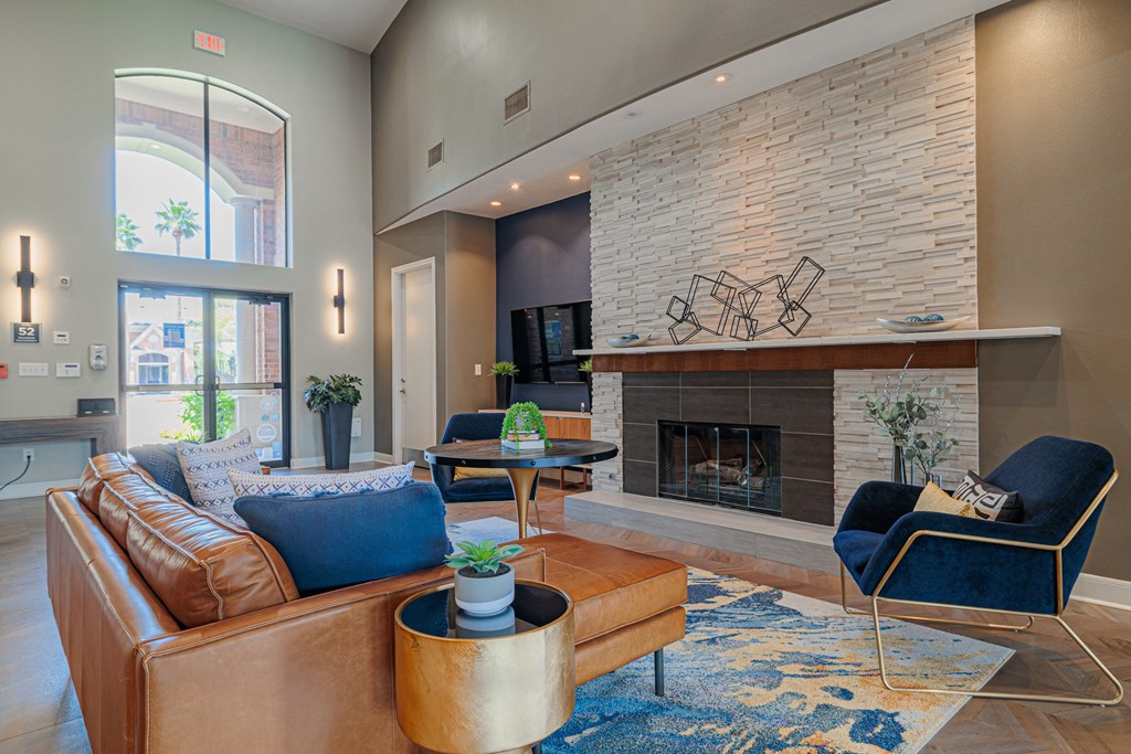 a living room with a leather couch and chair in front of a fireplace