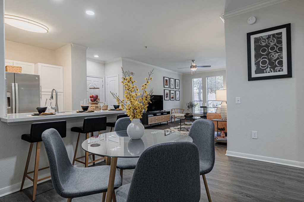 a dining area with a table and chairs and a kitchen in the background