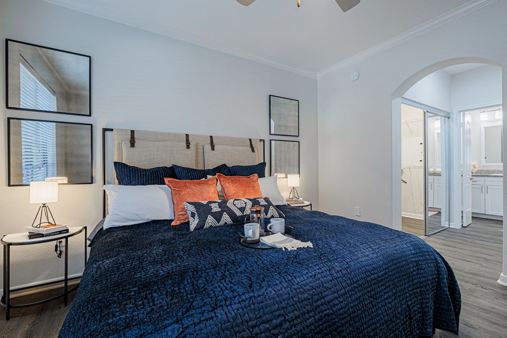 a bedroom with a blue bedspread and orange pillows