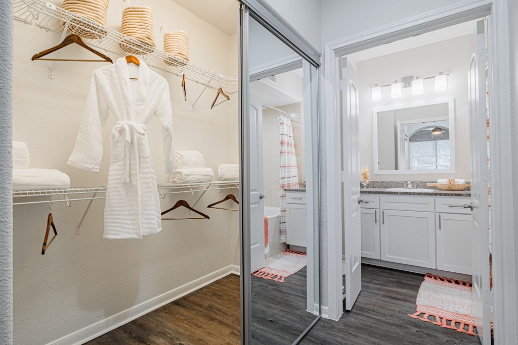 a white robe hangs on a hangar in a white bathroom