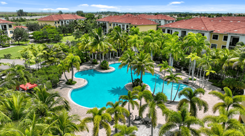 A swimming pool surrounded by palm trees and a resort.