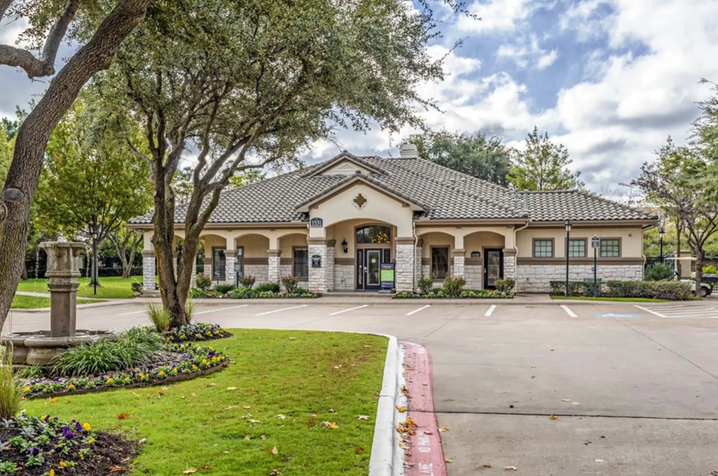 the front of a house with a parking lot and trees