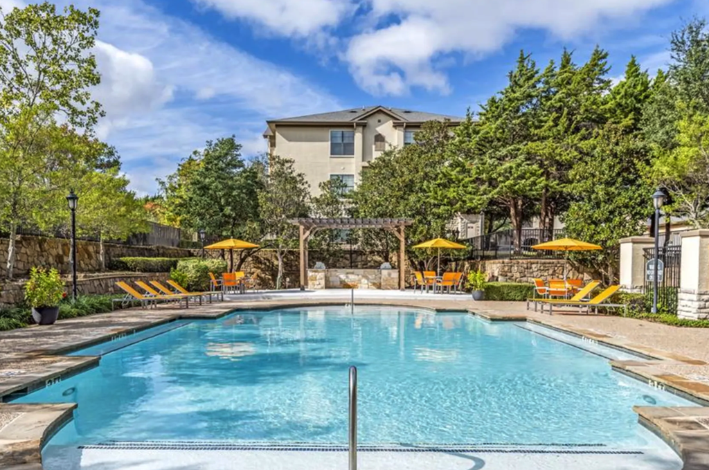 a swimming pool with trees and a building in the background