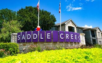 a sign for the saddle creek neighborhood in front of a house