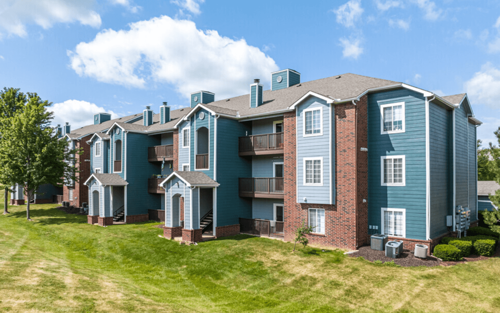 an apartment building with blue and red brick exterior and green grass
