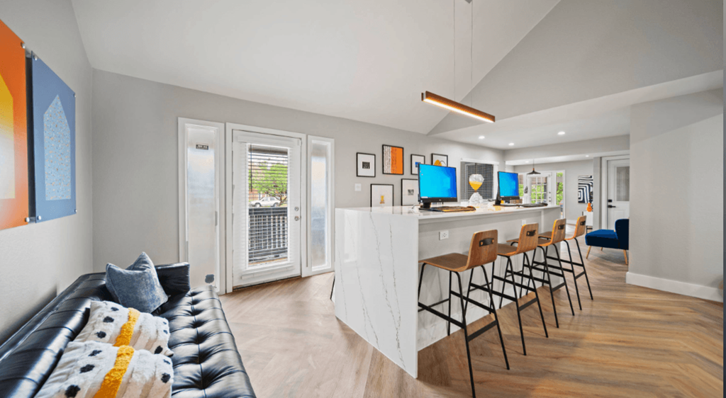a living room with a kitchen and a bar with chairs