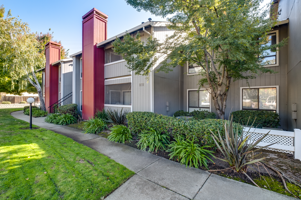 the walkway in front of an apartment building with a sidewalk