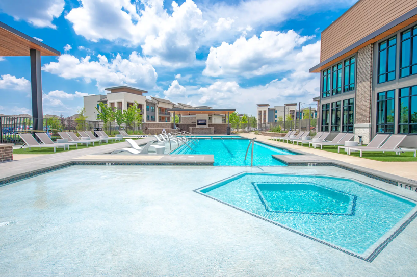 a large swimming pool with lounge chairs and a building in the background