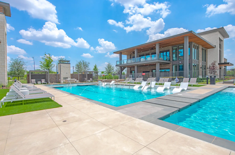 a swimming pool with lounge chairs and a building in the background