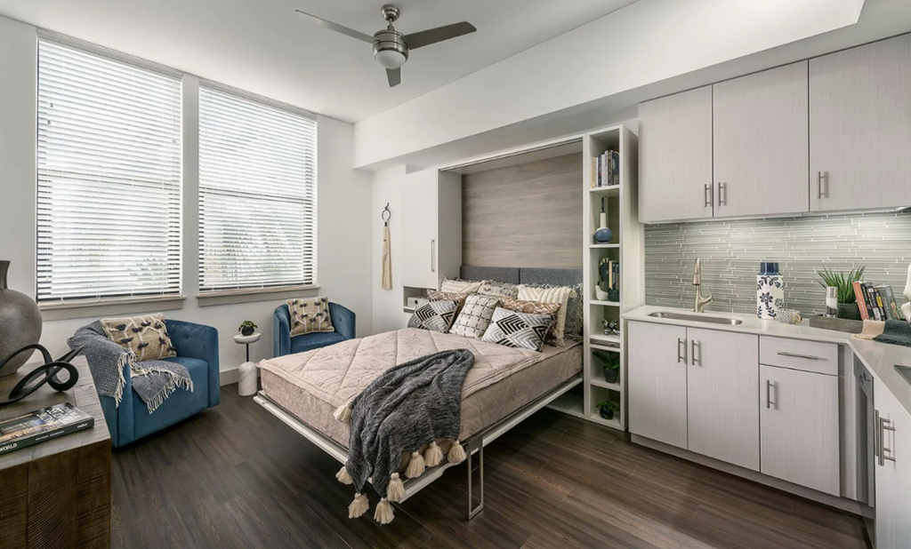 A bedroom with a bed, a chair, and a cabinet.
