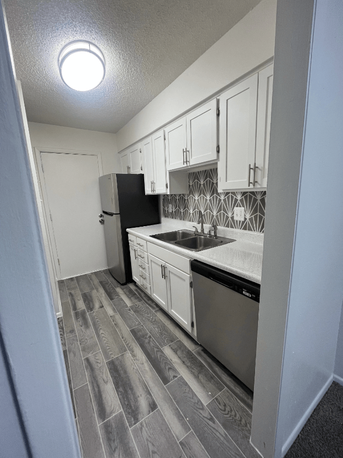 an empty kitchen with white cabinets and stainless steel appliances
