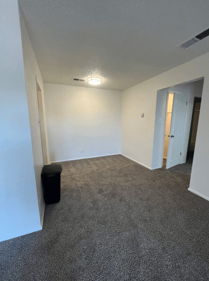 an empty living room with carpeting and white walls