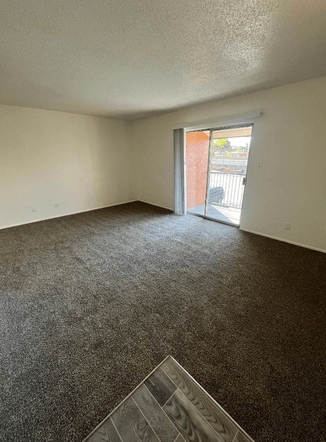 an empty living room with a door to a balcony