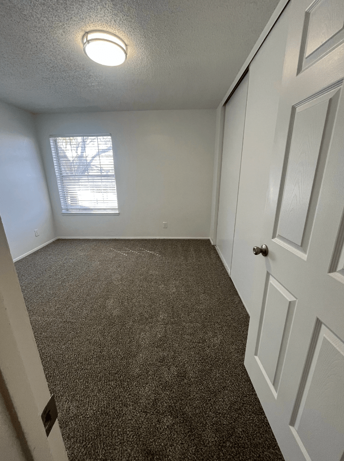 an empty room with a carpeted floor and a window