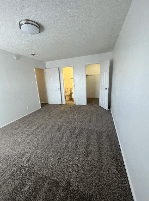 an empty living room with carpeting and white walls