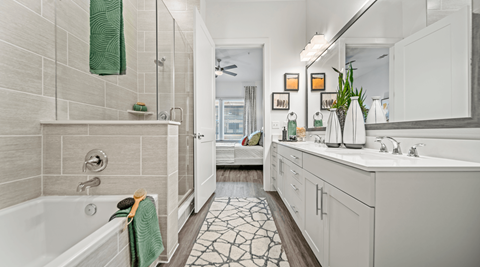 A bathroom with a white tub and a green towel.