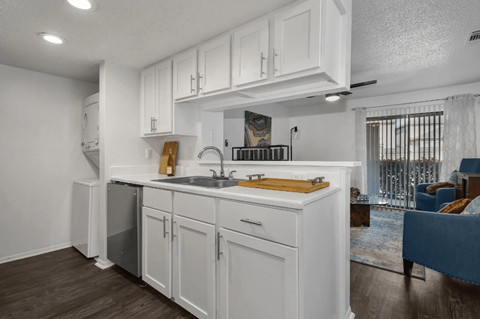 A kitchen with white cabinets and a wooden cutting board on the counter.