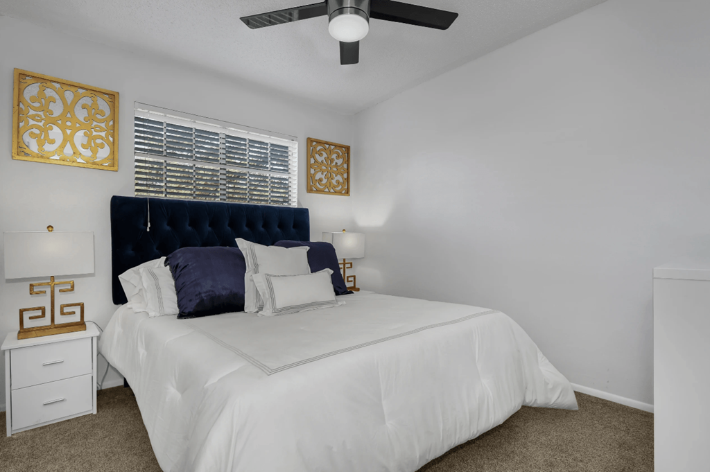 A bedroom with a white bed and a ceiling fan.